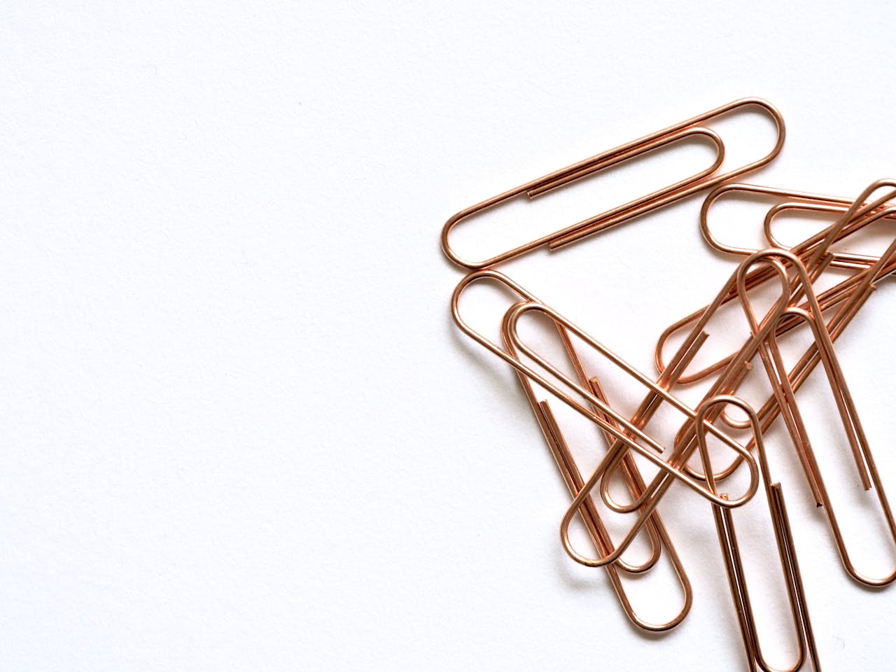 Copper paperclips arranged on a white background, highlighting modern office supplies.